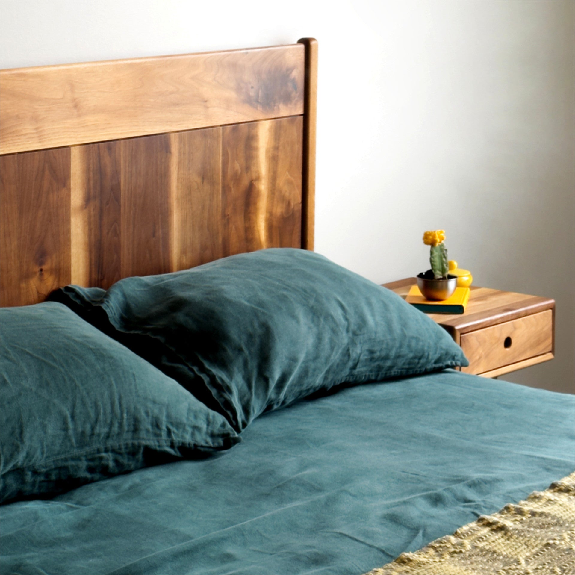 walnut bed frame made from solid walnut with green linen set and a matching nightstand 